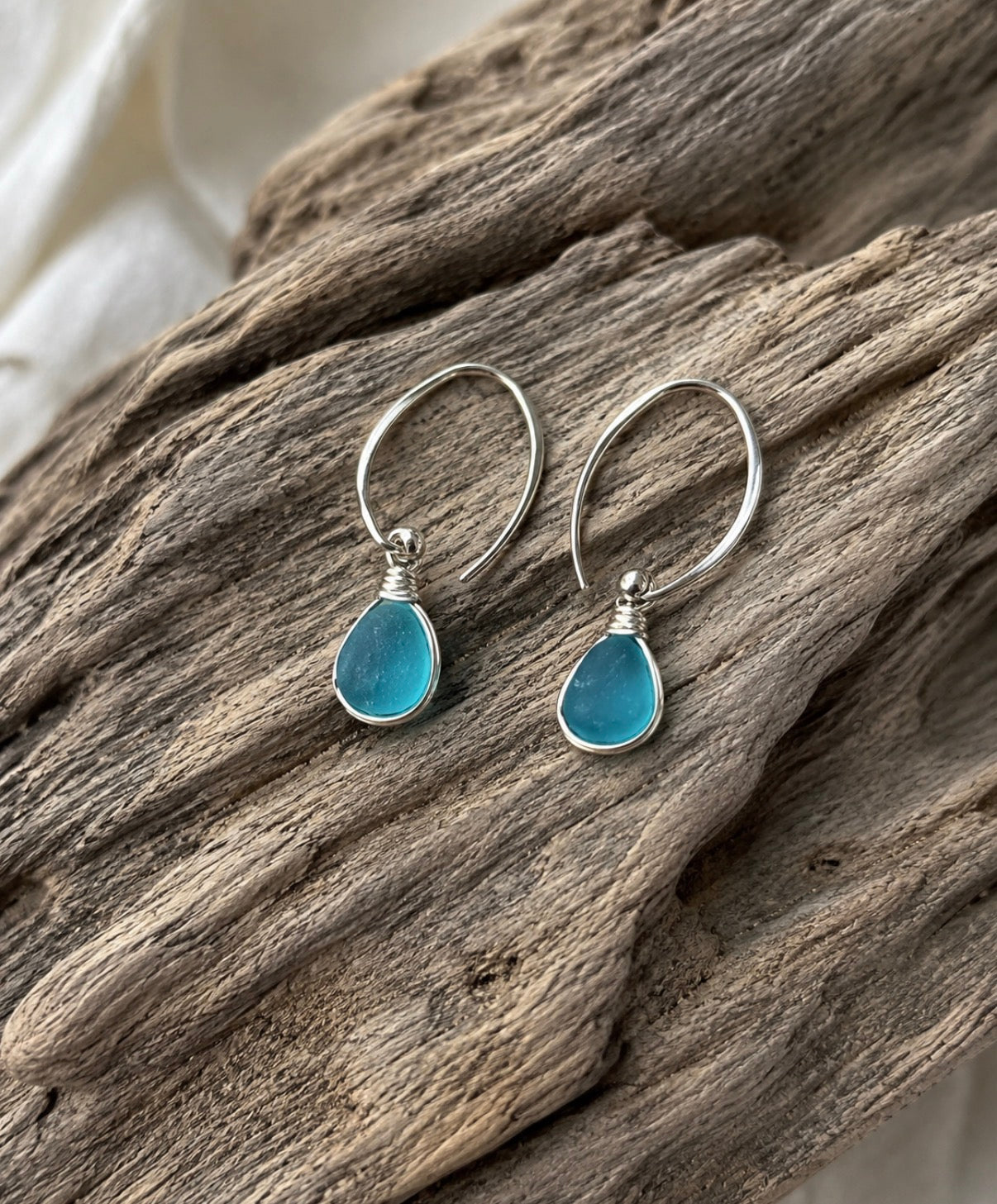 Aqua sea glass earrings on driftwood