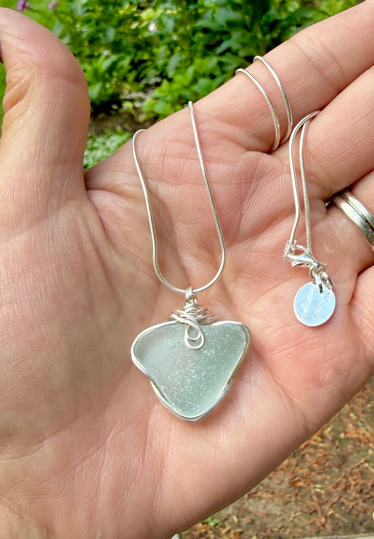 Natural heart sea glass pendant held in hand