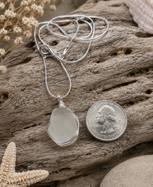 White frosted sea glass pendant wire wrapped in sterling silver, quarter size, on driftwood