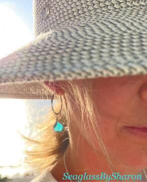 light blue sea glass earrings hanging on sand dollar