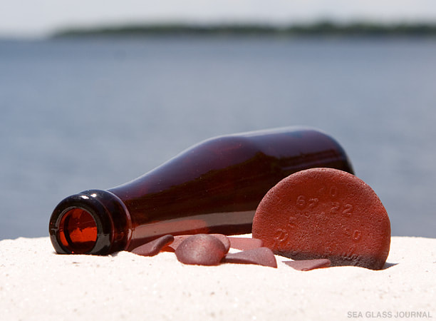Red Schlitz bottle on sandy beach shore